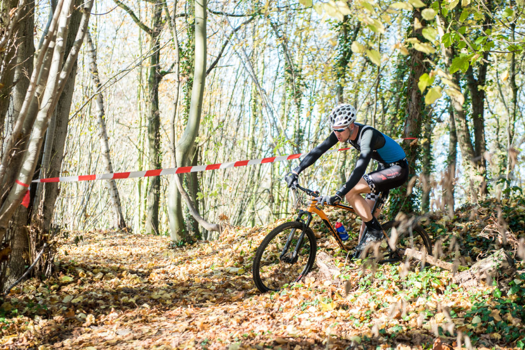 Photo couleur d'un VTTiste tournant dans un bois pour amorcer une descente