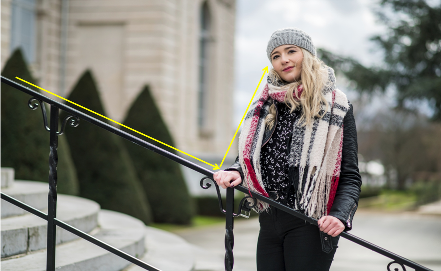 Portrait d'une femme debout dans un escalier et se tenant à la rampe avec un bâtiment en arrière-plan